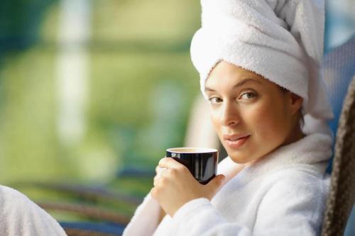 a woman in a robe holding a cup of coffee at Hotel HerzogsPark in Herzogenaurach