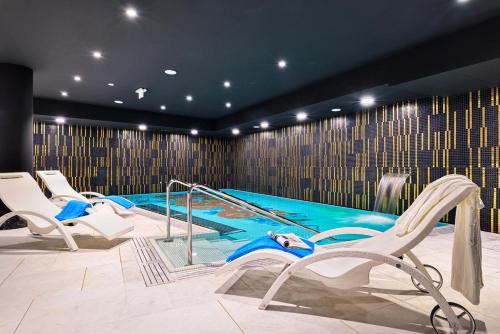 een zwembad met witte stoelen en een zwembad bij Hotel Ferreus Modern Art Deco in Krakau