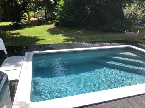 a swimming pool with blue water in a backyard at PAUSE NATURE SORBAIS Gite de groupe avec Piscine, Spas, Sauna et Hammam Shower avec 8 chambres et 8 salles de bain, grande cuisine et grande salle de vie in Sorbais