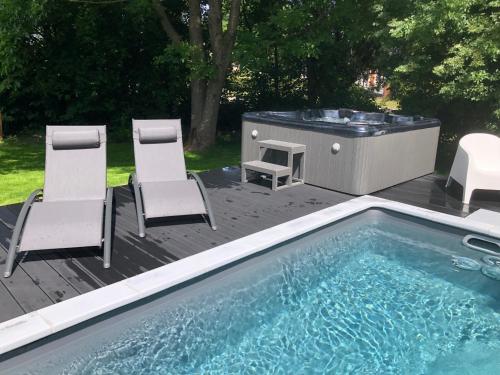 a swimming pool with chairs and a hot tub at PAUSE NATURE SORBAIS Gite de groupe avec Piscine, Spas, Sauna et Hammam Shower avec 8 chambres et 8 salles de bain, grande cuisine et grande salle de vie in Sorbais