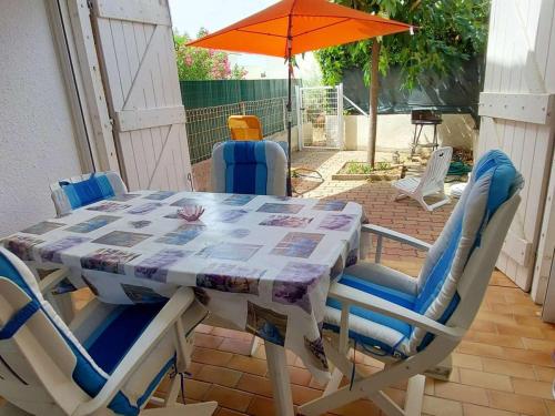 une table avec des chaises et un parasol sur une terrasse dans l'établissement Studio cabine RDC, proche plage et commerces, terrasse, WiFi gratuit, park 1 voiture, 4 couchages - FR-1-423-230, au Grau-dʼAgde