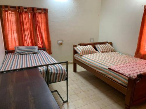 a bedroom with two beds and red curtains at Kamala Holiday Home in Mysore