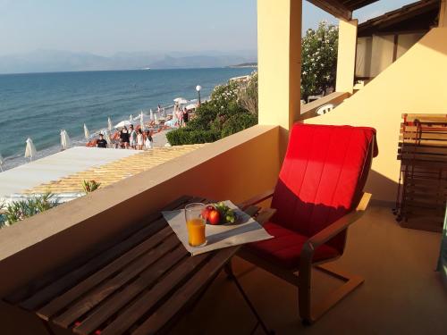 una sedia rossa seduta su un balcone con vassoio di frutta di Beatrice's apartment ad Acharavi