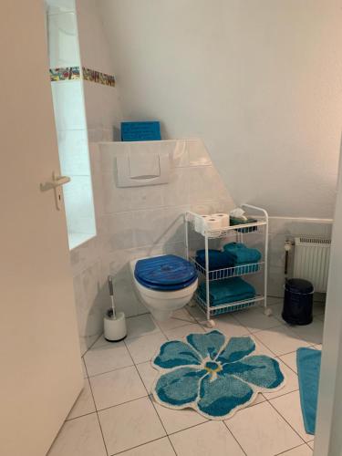 a bathroom with a blue toilet and a blue flower rug at Ferienwohnung Lehringen in Kirchlinteln