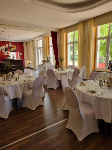 a dining room with white tables and white chairs at Kulturhotel Kaiserhof in Bad Liebenstein