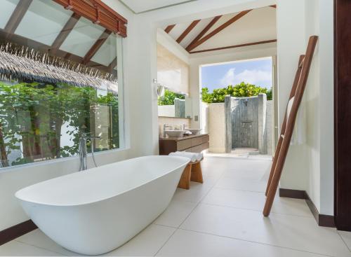 a white bathroom with a tub and a large window at Heritance Aarah - Premium All Inclusive - 40 Minutes away from Male by Seaplane in Raa Atoll