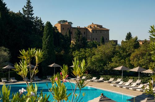 a beach with a pool, chairs, tables, and umbrellas at Toscana Resort Castelfalfi in Castelfalfi