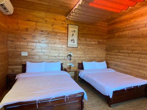 two beds in a room with wooden walls at 三仙台星辰民宿 in Chenggong