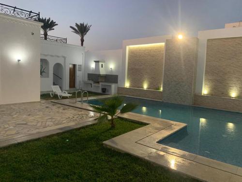 uma villa com piscina à noite em La casa blanca em Houmt Souk