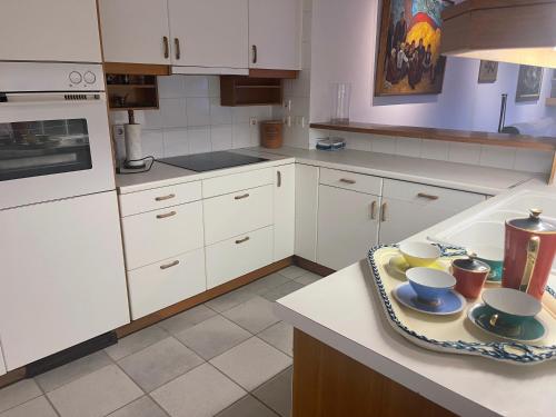 a kitchen with white cabinets and a counter with cups and plates at Sea-side 3 BEDROOM- BEACH HOUSE in Poros