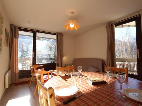 une salle à manger avec une table, des chaises et des fenêtres dans l'établissement Appartement 6 Pers. avec Balcon, Proche Navette et Parking Gratuit à Serre-Chevalier - FR-1-330E-92, à Saint-Chaffrey