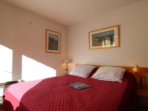 - une chambre avec un lit rouge et un livre dans l'établissement Appartement Saint-Chaffrey , 2 pièces, 6 personnes - FR-1-330E-92, à Saint-Chaffrey