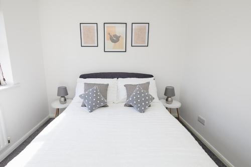 a bedroom with a white bed with pillows at Modern 2 Bed House Near Queens Medical Centre in Nottingham