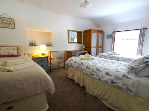 een slaapkamer met 2 bedden en een raam bij Royal Oak Cottage in Amlwch
