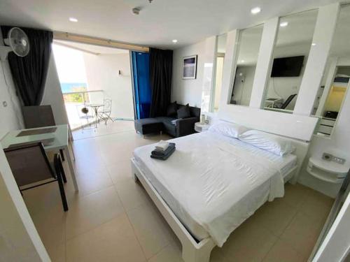 a bedroom with a white bed and a living room at Sands Condo Studio 14 by ThaiminatorPattaya in Pattaya South