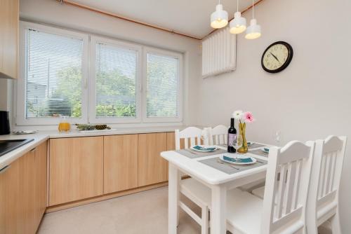 a kitchen with a table and chairs and a clock on the wall at Gdańska Two-bedroom Apartment Brzeźno Beach by Renters in Gdańsk