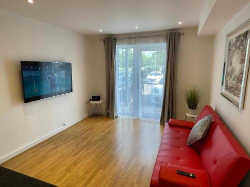 a living room with a red couch and a television at Moda Wigan - Stylish 2 Bed Apartment Central Wigan in Wigan