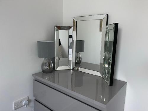 a dresser with two mirrors and a lamp on it at Moda Wigan - Stylish 2 Bed Apartment Central Wigan in Wigan