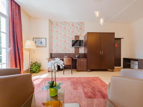 a living room with a table and a desk at Kulturhotel Kaiserhof in Bad Liebenstein