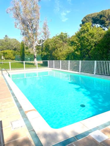 une piscine d'eau bleue et une clôture blanche dans l'établissement Cap d'Antibes - Garoupe - Pool, Tennis privé, à 300m de la plage, à Antibes