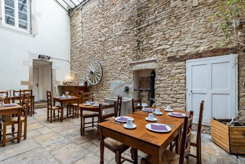 een restaurant met houten tafels en stoelen en een bakstenen muur bij Hôtel des Tonneliers in Beaune