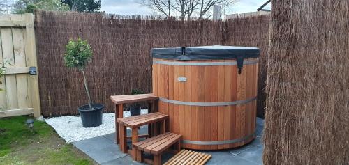 a wooden barrel with two benches next to a fence at Moe Marie Sleep Peacefully in Turangi
