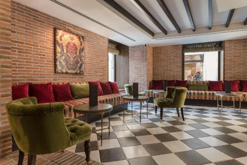 a lobby with a couch and chairs and a brick wall at Palacio Solecio, a Small Luxury Hotel of the World in Málaga