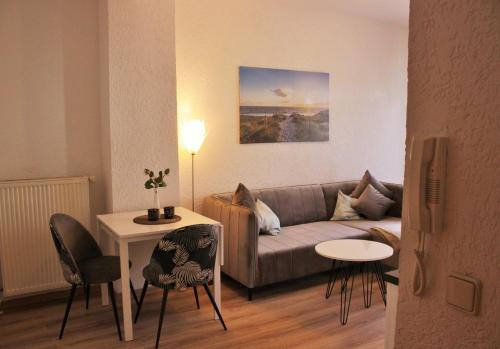 ein Wohnzimmer mit einem Sofa, einem Tisch und Stühlen in der Unterkunft Gästewohnung Merci in Merseburg