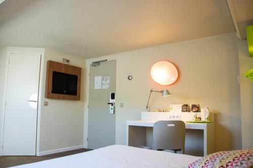 1 dormitorio con cama, escritorio y lámpara en Campanile Dunkerque Sud - Loon Plage, en Loon-Plage