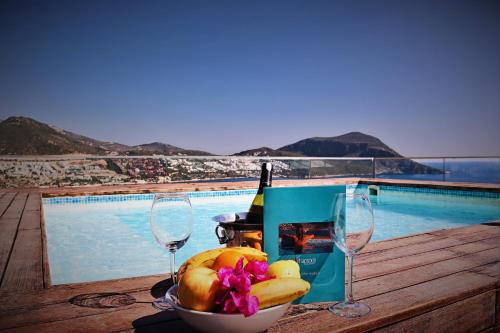 a bowl of fruit and wine glasses next to a pool at Rhapsody Hotel & Spa Kalkan in Kalkan