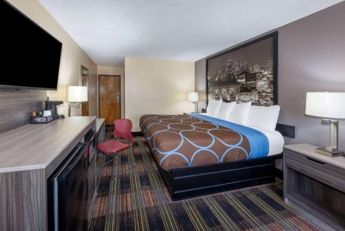 una camera d'albergo con un letto e una TV a schermo piatto di Super 8 by Wyndham Kansas City at Barry Road/Airport a Kansas City