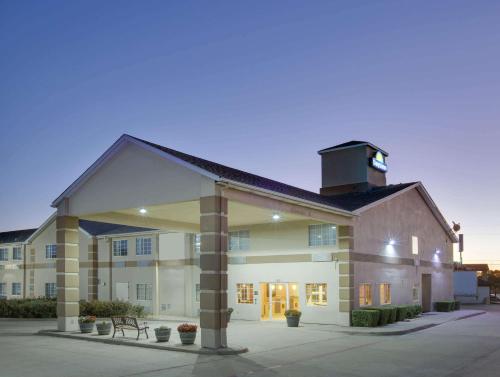a largeartment building with a building with a rooftop at Days Inn by Wyndham Mesquite Rodeo TX in Mesquite