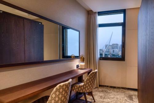 a hotel room with a desk and two chairs and a window at Ramada Jerusalem Hotel in Jerusalem