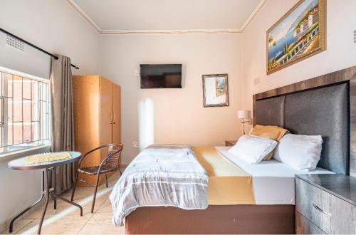 1 dormitorio con cama, mesa y ventana en Whitehouse Lodge, en Benoni