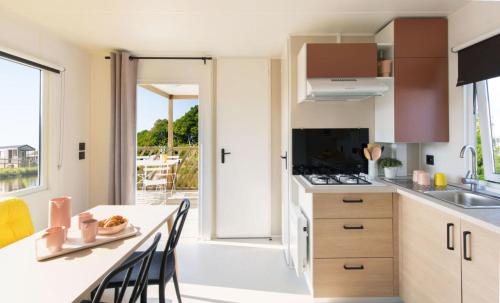a kitchen with a table with chairs and a counter top at Camping La Baie des Voiles in Porto-Vecchio