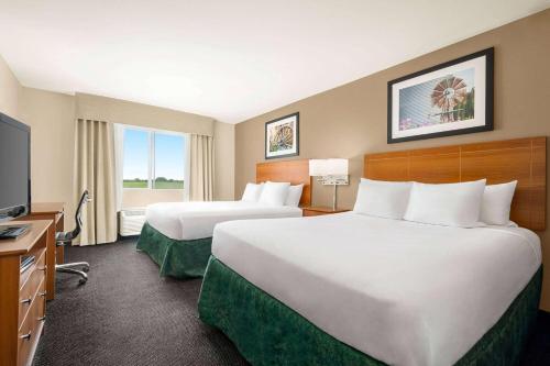 a hotel room with two beds and a flat screen tv at Baymont by Wyndham Fremont in Fremont