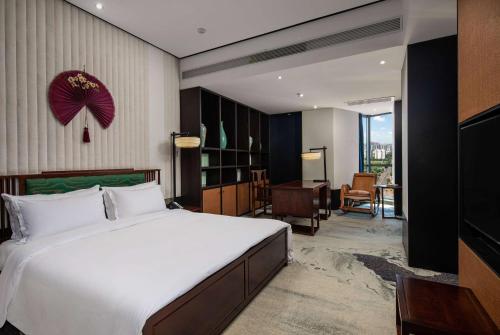 um quarto com uma grande cama branca e uma secretária em Wingate by Wyndham Changsha Yuhua em Changsha
