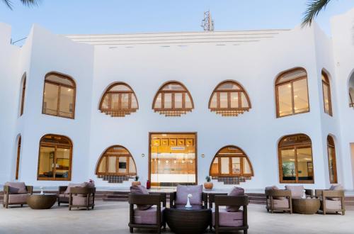 a white building with chairs and tables and windows at Safir Dahab Resort in Dahab