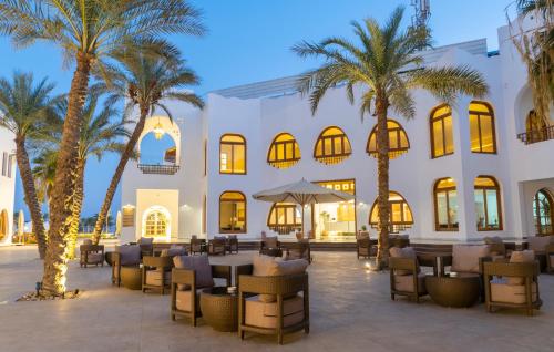 a hotel patio with palm trees and tables at Safir Dahab Resort in Dahab