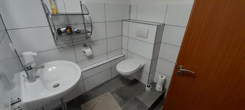 La salle de bains blanche est pourvue de toilettes et d'un lavabo. dans l'établissement Gästezimmer Salzgitter II in Wolfenbüttel, à Wolfenbüttel
