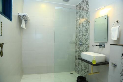 a white bathroom with a sink and a shower at Shiv Kothi - Homestay in Agra