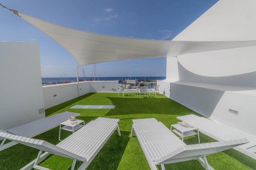 a balcony with white furniture and green grass at Vista al Muelle by HH in Puerto del Carmen