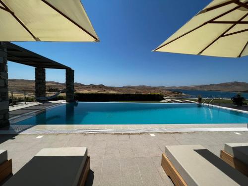 a swimming pool with two umbrellas on a patio at VILLA MIRSINI in Tsimándria