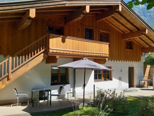 a house with a balcony and an umbrella at Ferienwohnung am Wald in Waidring