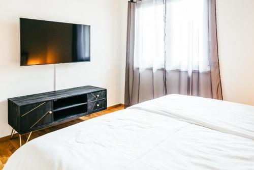 a bedroom with a bed and a flat screen tv at Love Suite in Mörbisch am See