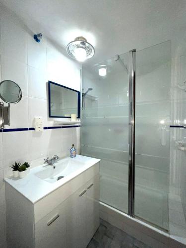 a white bathroom with a sink and a shower at Admirals Suite, Gibraltar in Gibraltar