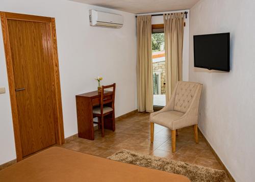 a room with a chair and a desk and a television at Casas Campo Cimo da Quinta in Miranda do Douro