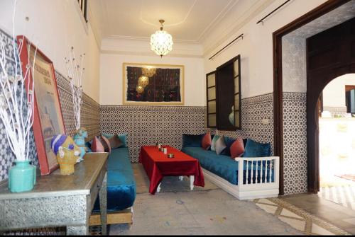 un soggiorno con divano blu e tavolo rosso di Riad New Moon a Marrakech