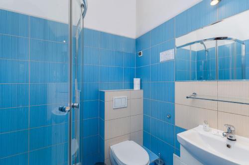 Daniel Griffin Aparthotel by Artery Hotels في كراكوف: حمام من البلاط الأزرق مع مرحاض ومغسلة