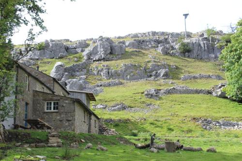 an old stone house in a field with a hill at Crina Bottom - Offgrid Mountain Escape in the Yorkshire Dales National Park in Ingleton